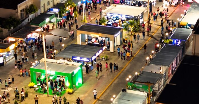 Público circulando entre estandes iluminados de feira à noite